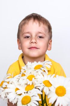 A cute boy with a beautiful bouquet of large daisies. Portrait of a child, funny and cute facial expression. Selective focus. A postcard for the celebration of the day of family, love and fidelity.