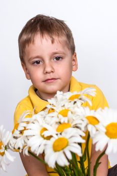 A cute boy with a beautiful bouquet of large daisies. Portrait of a child, funny and cute facial expression. Selective focus. A postcard for the celebration of the day of family, love and fidelity.