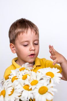 A cute boy with a beautiful bouquet of large daisies. Portrait of a child, funny and cute facial expression. Selective focus. A postcard for the celebration of the day of family, love and fidelity.