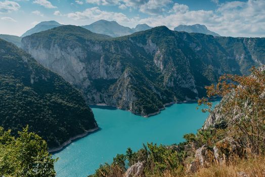 The concept of eco-tourism and active recreation. National Park. Mountain Emerald lake in the wooded mountains. Sunny day in autumn.