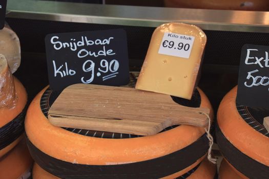 Traditional Dutch cheeses on display in a store (text on labels: price and product information in Dutch, old cheese but soft enough to cut)