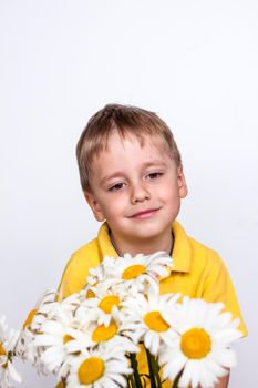 A cute boy with a beautiful bouquet of large daisies. Portrait of a child, funny and cute facial expression. Selective focus. A postcard for the celebration of the day of family, love and fidelity.