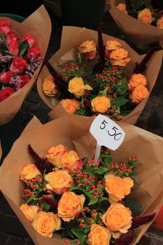 Bouquets with roses at a market, wrapped in paper (text on tags: prices in euro)