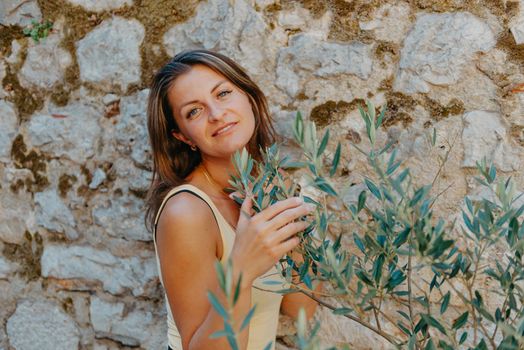 Girl tourist walking through ancient narrow street on a beautiful summer day in MEDITERRANEAN MEDIEVAL CITY , OLD TOWN bUDVA, MONTENEGRO. Young beautiful cheerful woman walking on old street at tropical town. Pretty girl looking at you and smiling