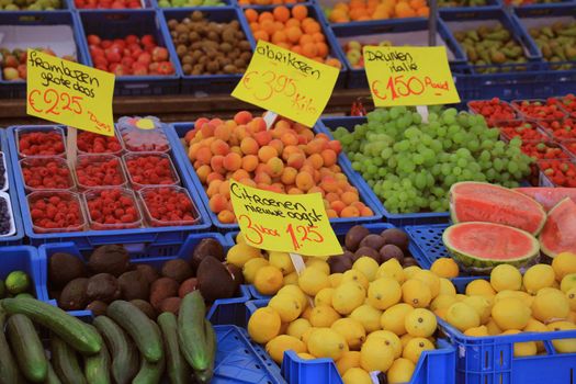 Fresh fruit on a market stalll (text on tags: names and prices of various fruits in Dutch, raspberries, apricots, grapes from Italy and fresh harvested lemons )