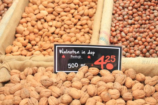 Fresh unpealed nuts on a market stall (text on tags: names and prices of various nuts in Dutch, walnuts, Pecan, almonds and hazel)