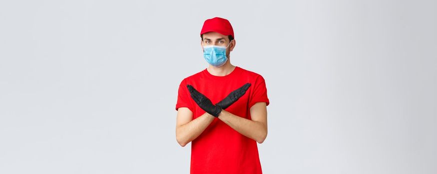 Covid-19, self-quarantine, online shopping and shipping concept. Courier disapprove contact during shipping goods, refuse or rejecting work without face mask and gloves, make cross sign.