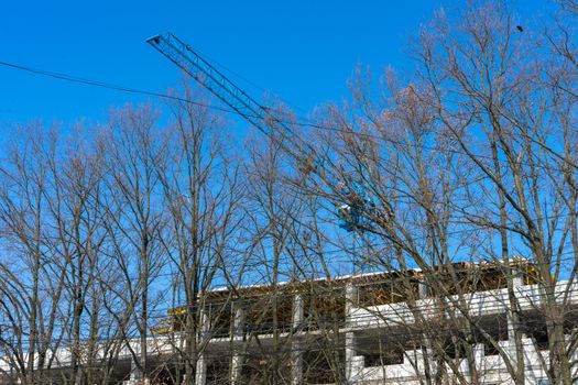 A shot of a high-rise construction crane against a blue spring sky. Building landscape