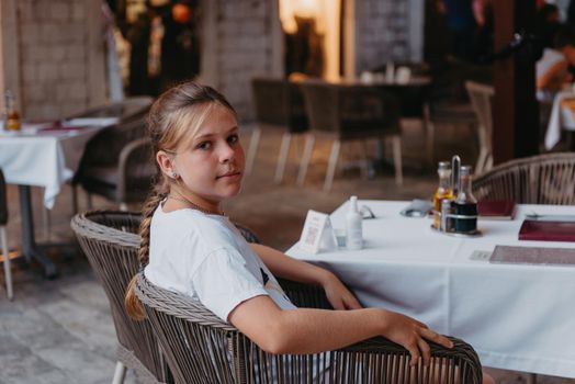 Girl Tourist Resting in the Ancient Narrow Street On A Beautiful Summer Day In MEDITERRANEAN MEDIEVAL CITY, OLD TOWN KOTOR, MONTENEGRO. Young Beautiful Cheerful Woman Walking On Old Street