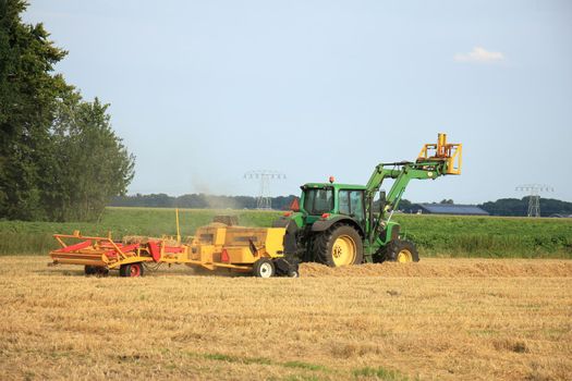 Tractor in a field, harvesting grain in the late afternoon sun