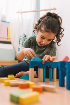 little girl playing concentrated in the floor with colorful wooden building block toys at home or kindergarten, educational toys for creative children