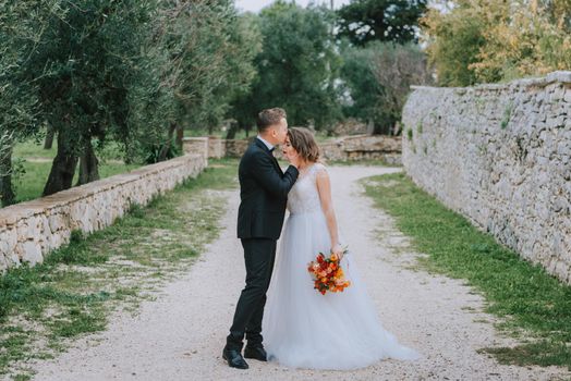 Happy stylish smiling couple walking in Tuscany, Italy on their wedding day. The bride and groom walk down the street by the hands. A stylish young couple walks. Husband and wife communicate nicely. Lovers run through the streets of the city.