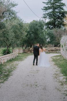 Happy stylish smiling couple walking in Tuscany, Italy on their wedding day. The bride and groom walk down the street by the hands. A stylish young couple walks. Husband and wife communicate nicely. Lovers run through the streets of the city.