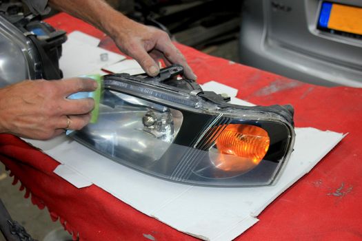 Man refurbishing a car headlight with clear coating