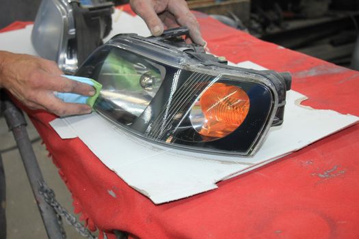 Man refurbishing a car headlight with clear coating