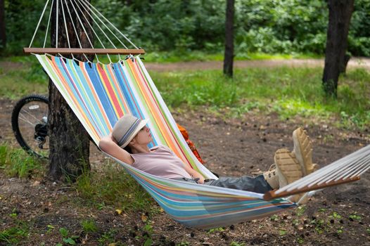 Caucasian woman lies in a hammock in a pine forest.