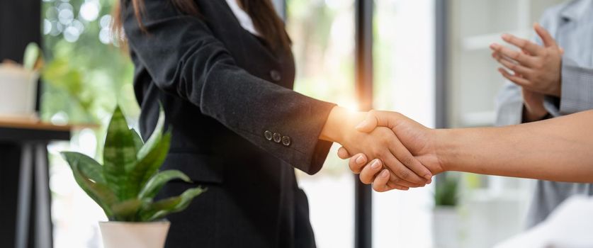 Millennial businessmen colleagues shaking hands on meeting in office, diverse enterpreneurs striking good deal, multiethnic teammates succeed in common project work.