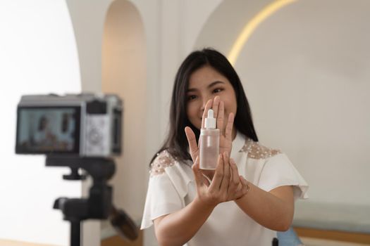 Pretty young woman holding a cosmetic product in front of the camera while speaking about cosmetic tools.