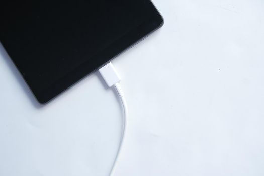 charging s digital tablet with a cable on white background ,