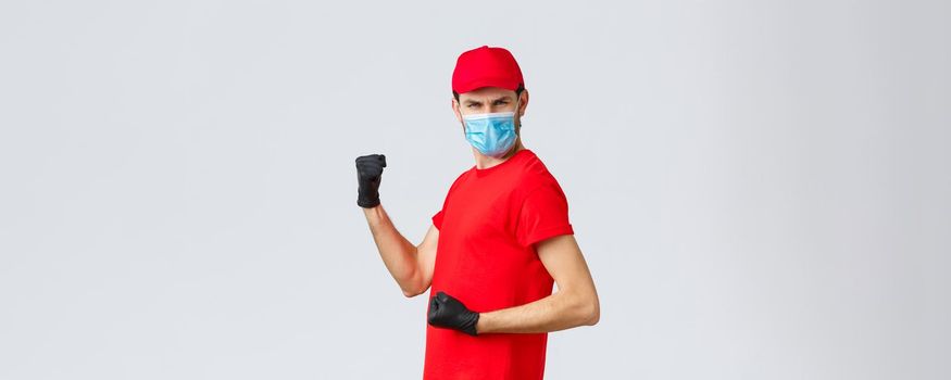 Covid-19, self-quarantine, online shopping and shipping concept. Energized, excited delivery guy do champion dance, fist pump and looking empowered, celebrate success, rejoicing in courier outfit.