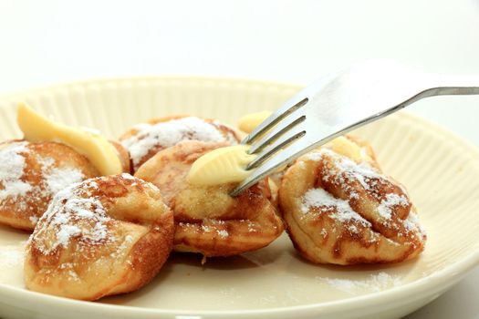 Poffertjes, Dutch small, fluffy pancakes, served with powdered sugar and butter.