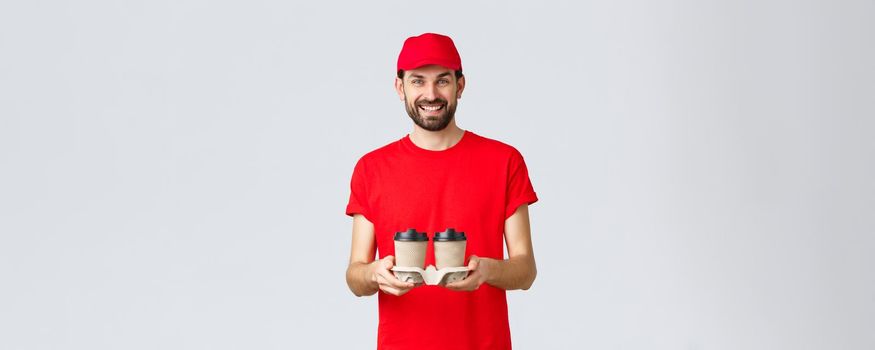 Food delivery, quarantine, stay home and order online concept. Smiling courier in red cap and t-shirt bring coffee to clients. Employee handing beverege via drive through window.