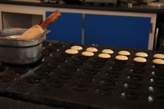 Poffertjes, Dutch small, fluffy pancakes, made on hot cast iron plate, served with powdered sugar and butter.