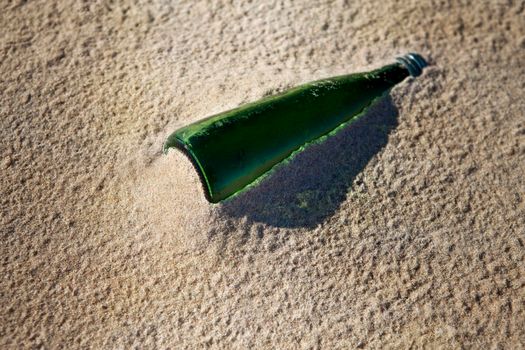 Old glass bottle stranded on the sand of the beach after the tide