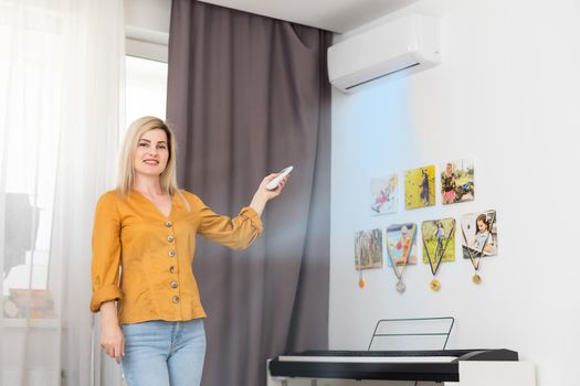 Air conditioner inside the room with woman operating remote controller. Air conditioner with remote controller.