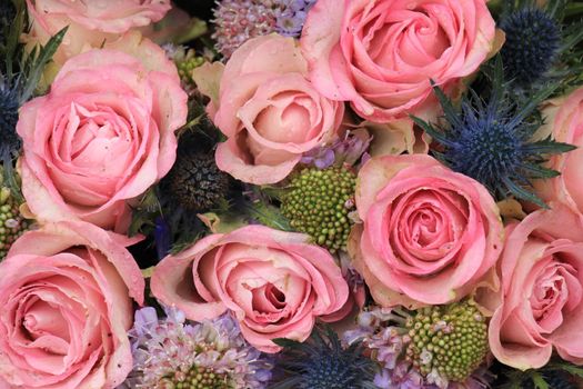 Pink roses and blue sea holly in a wedding flower arrangement