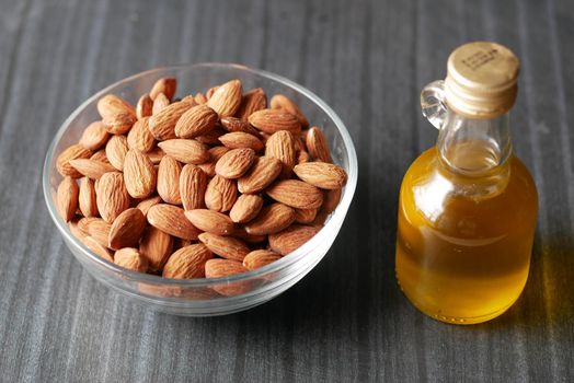 almond nuts in a bowl and oil in a jar on table ,