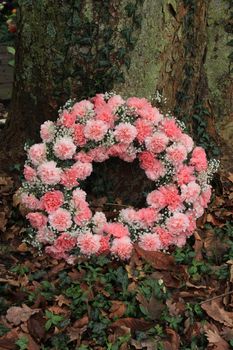 Pink sympathy or funeral flowers near a tree at a cemetery