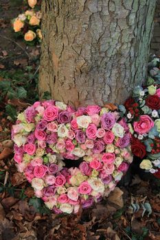 Heart shaped sympathy or funeral flowers near a tree