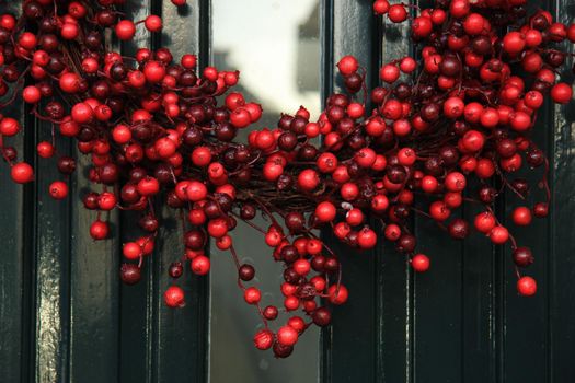 Berry christmas wreath with decorations on a door