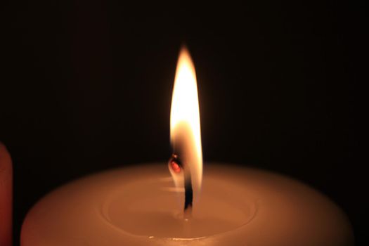 Burning candle in closeup, big flame and melted wax