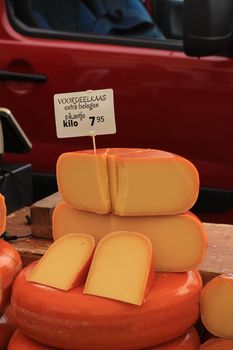 Traditional Dutch cheeses on display on a market stall, Text on tag, product and price information in Dutch: special offer, extra matured, spicy cheese.