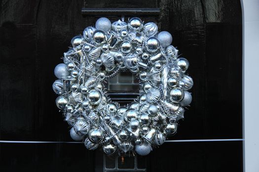 Silver christmas wreath with decorations on a door