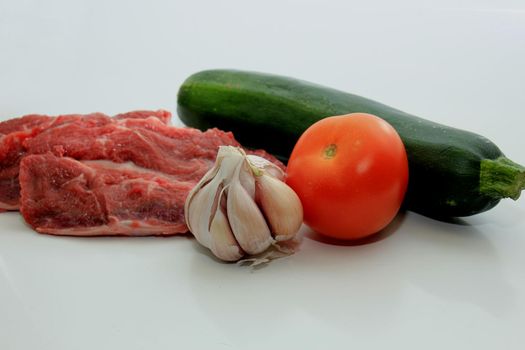 Raw beef, a zucchini or courgette, some garlic and a tomato
