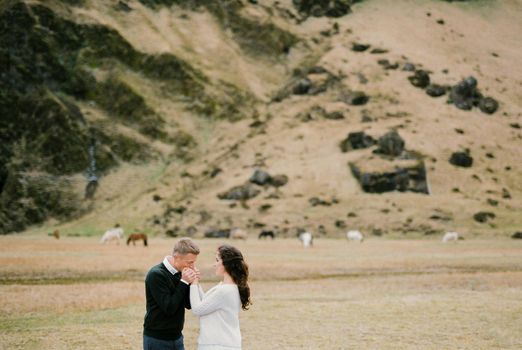 Groom kisses the hands of bride on the background of the mountains. Iceland. High quality photo