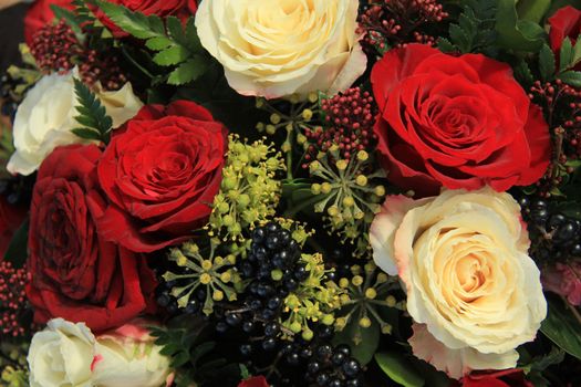 Red and white roses and berries in a bridal bouquet