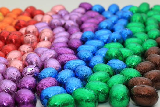 a group of foil wrapped chocolate easter eggs in rainbow colors