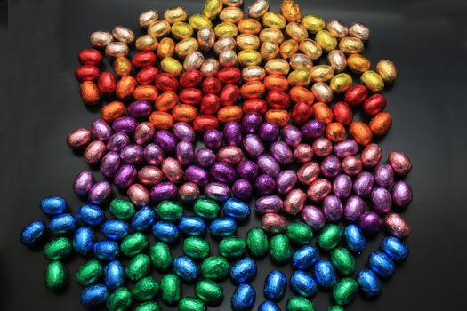 a group of foil wrapped chocolate easter eggs in rainbow colors