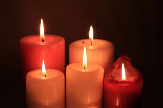 Group of burning candles in different heights and colors