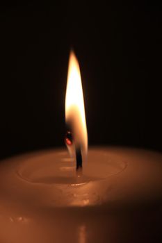 Burning candle in closeup, big flame and melted wax