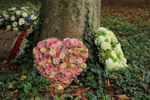 Heart shaped sympathy flowers  or funeral flowers near a tree