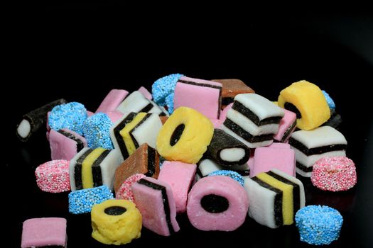 Stacked liquorice all sorts in different shapes, colors and sizes