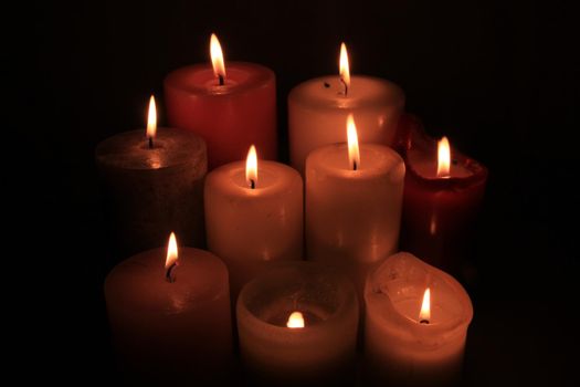 Group of burning candles in different heights and colors