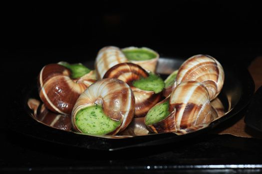 Escargots de Bourgogne on a metal plate in the oven