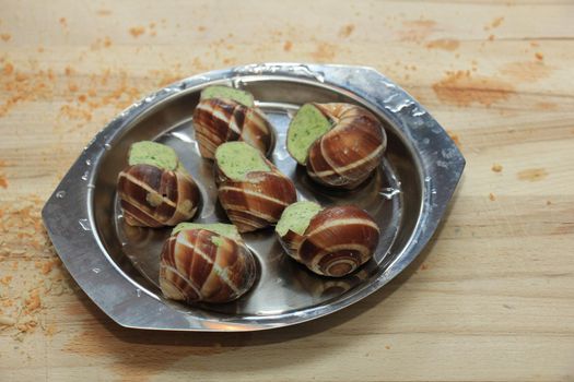 Escargots de Bourgogne on a metal plate ready to put in the oven
