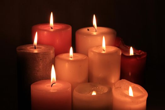 Group of burning candles in different heights and colors